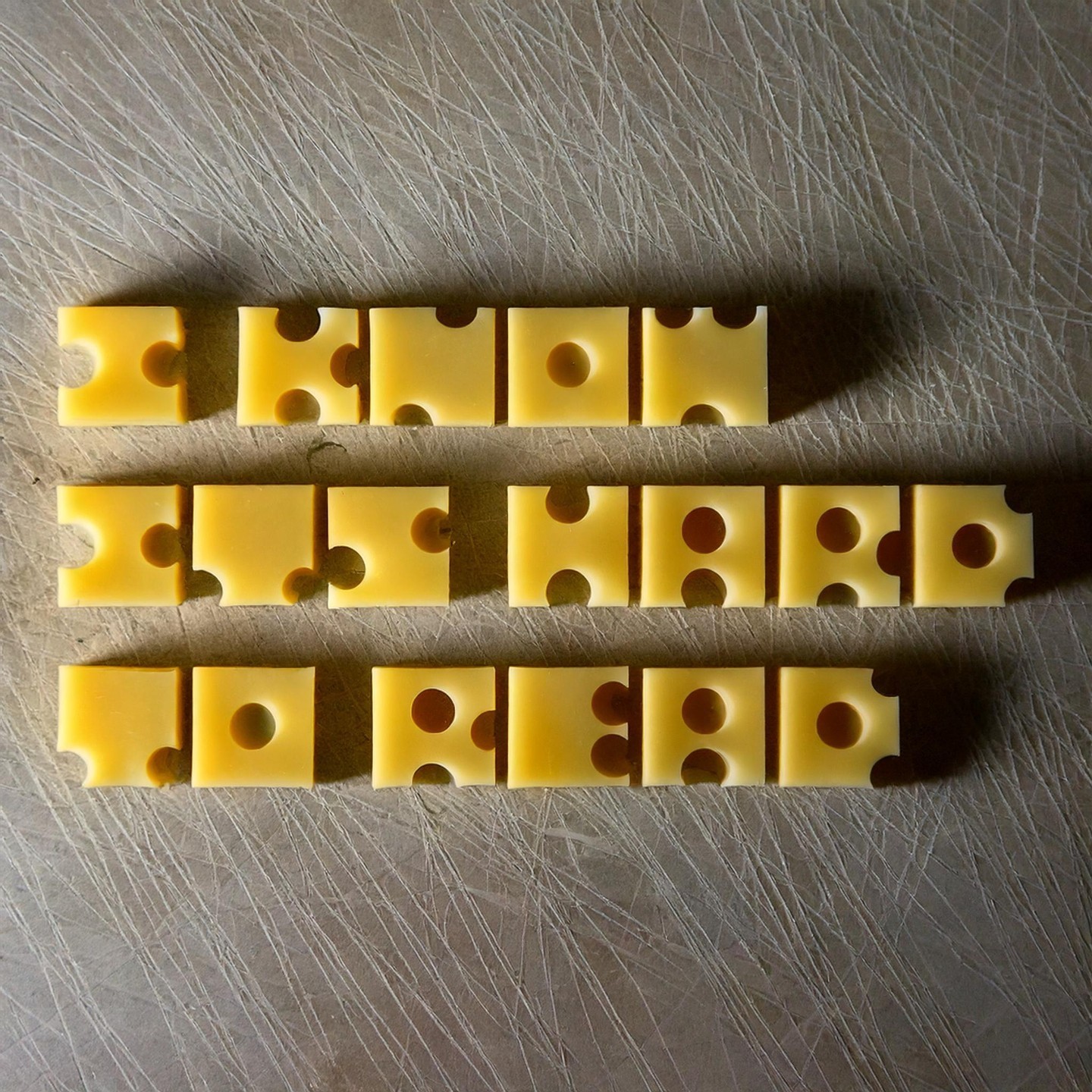 Photo of tiny cheese cubes with circular holes that makes them a kind of font. Text reads: I know it's hard to read"